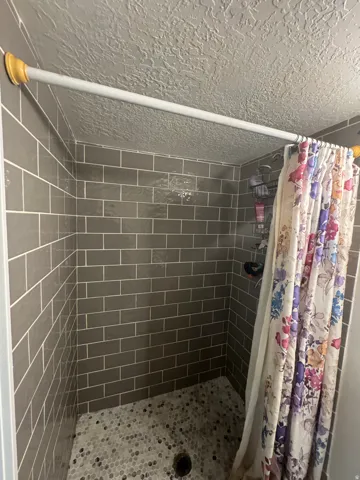 Subway tile shower surround with mosaic tile flooring