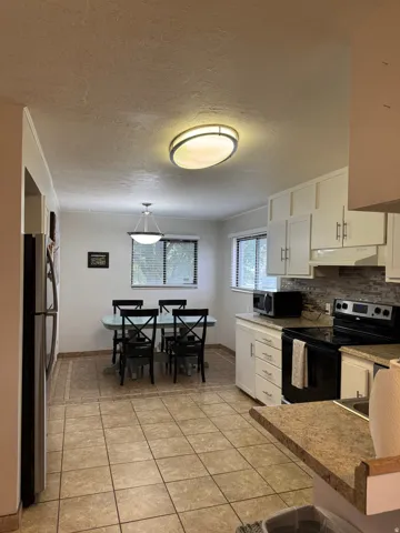 Kitchen featuring white cabinetry, stone-look countertops, and a tile backsplash
