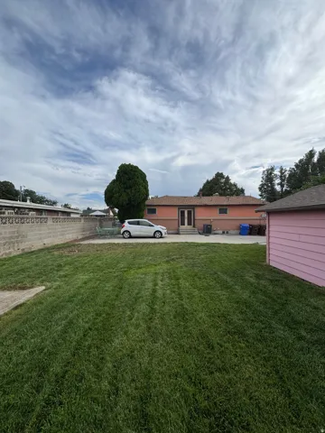 Expansive grassy yard with a concrete block privacy wall and established trees