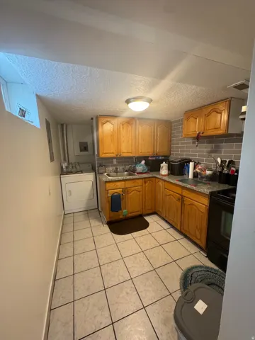 U-shaped kitchen layout featuring wood-finish cabinetry, a white tiled floor, and a gray subway tile backsplash