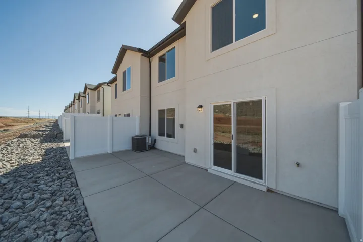 Private concrete patio with white vinyl fencing and exterior lighting