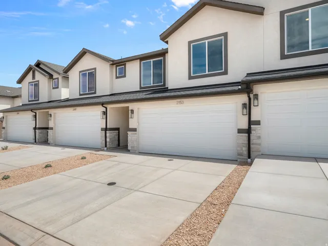Stucco exterior with stone accents, attached garages, dark trim windows, and concrete driveways