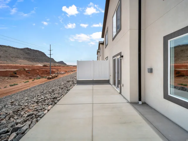 Exterior patio with concrete paving, white privacy fencing, and sliding glass doors