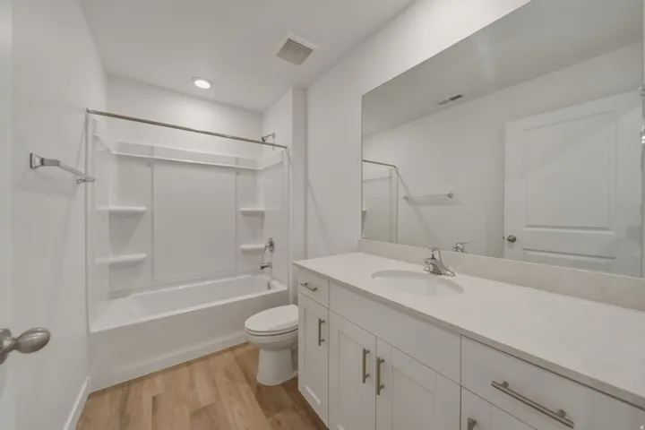 White vanity with a single basin sink and light-toned countertop