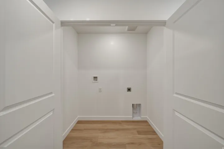 Dedicated laundry space featuring wood-finish flooring and bright white walls