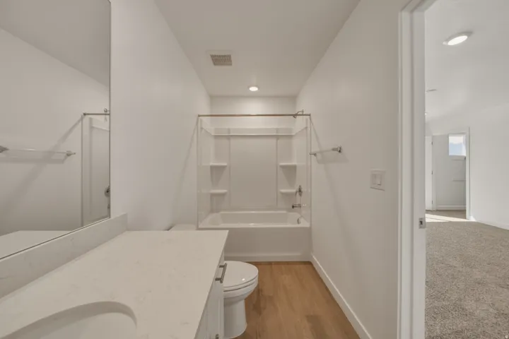 White vanity with an integrated sink, light-colored countertop, and a shower-over-tub combination