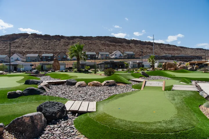 Miniature golf course featuring artificial turf, decorative rock landscaping, and multiple putting greens