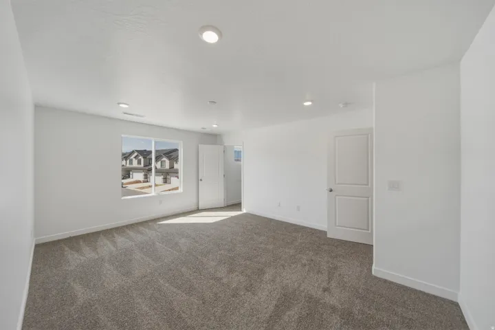 Recessed ceiling lighting, white walls, gray carpet flooring, white trim, and a white interior door