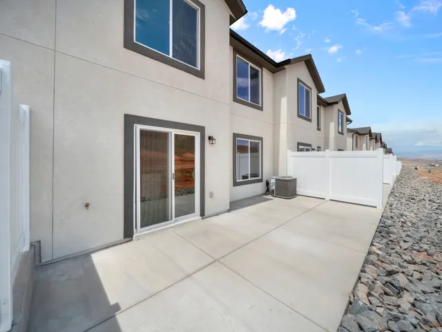 Paved concrete patio with white privacy fencing, stucco exterior, and sliding glass door access