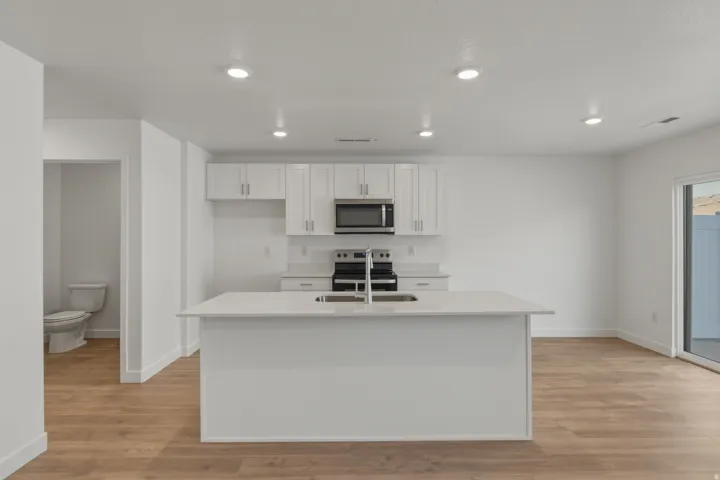 Kitchen featuring white cabinetry, stainless steel appliances, a center island with sink, recessed lighting, and wood-finish flooring