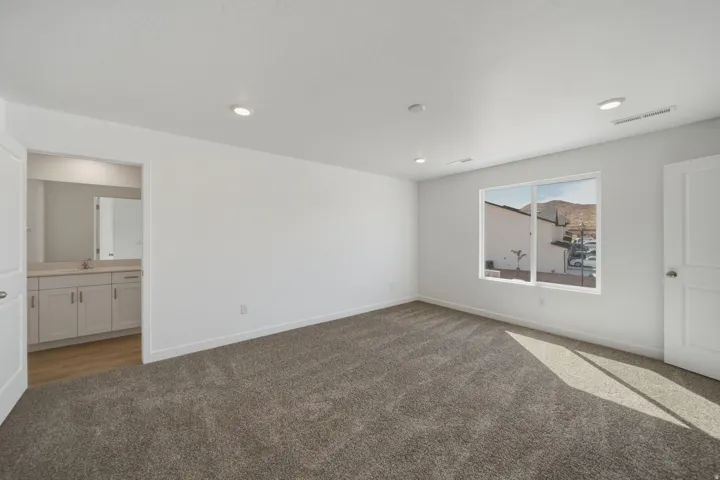 Spacious room with recessed lighting, light-colored walls, and neutral carpet