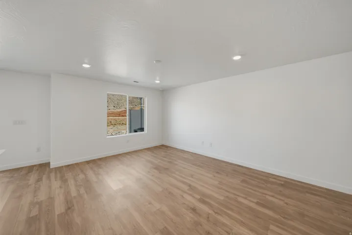 Wood-finish flooring, recessed lighting, and a window with a rock backdrop