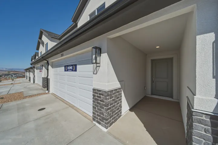 Exterior featuring a covered entryway, paneled front door, and an attached garage with a contemporary light fixture