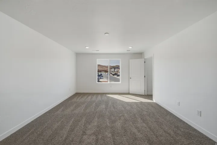 Spacious interior with neutral carpeting, white walls, recessed lighting, and a white window frame