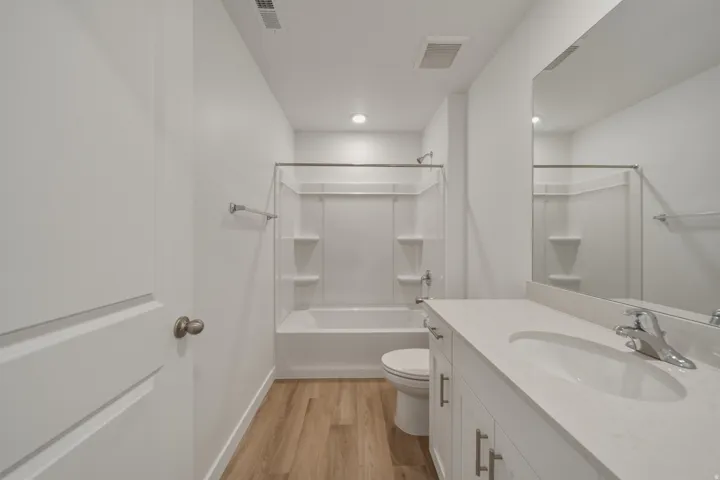 Bathroom featuring a single vanity with stone-finish countertop, undermount sink, and chrome faucet