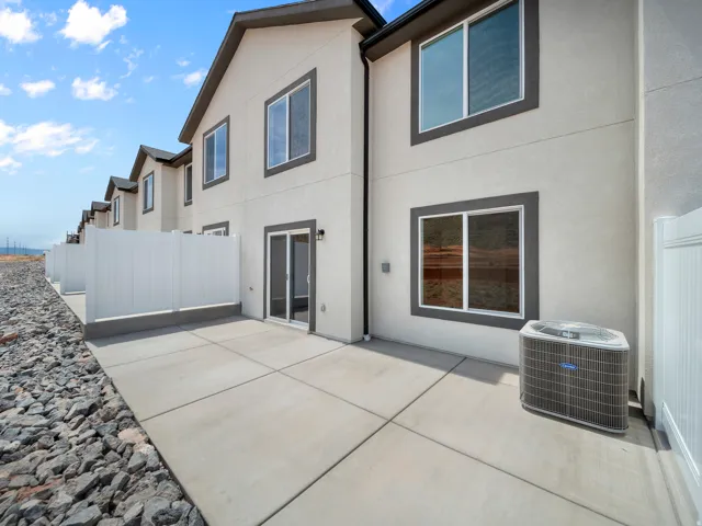 Private patio with concrete pavers and white vinyl fencing, featuring a sliding glass door entry and stucco exterior