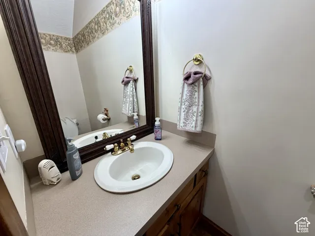 Single basin vanity with brass fixtures and an ornate framed mirror