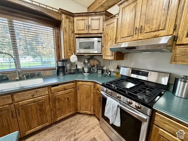 Warm wood cabinetry with abundant storage defines this kitchen, featuring stainless steel appliances including a gas range with multiple burners, built-in microwave, and matching refrigerator