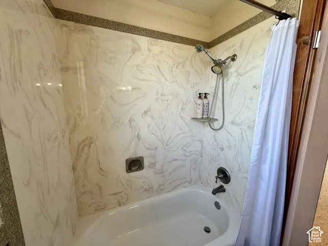 Bathtub with a shower system featuring a handheld showerhead, wall-mounted showerhead, and a fixed soap dish