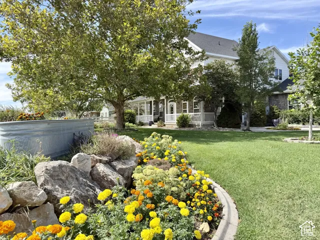 Manicured lawn with a curved paver border, vibrant floral landscaping, rock garden, and a galvanized raised garden bed