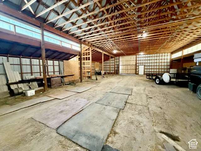 Spacious interior featuring exposed wood beam ceiling, corrugated metal walls, and a large overhead storage area