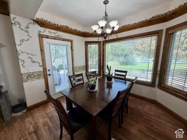 Wood-finish flooring, bay windows with blinds, glass-paned door, and overhead chandelier