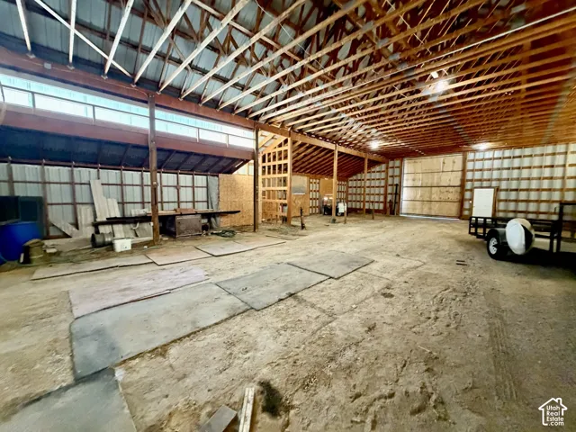 Spacious interior with exposed wood beam ceiling, corrugated metal walls, and concrete flooring