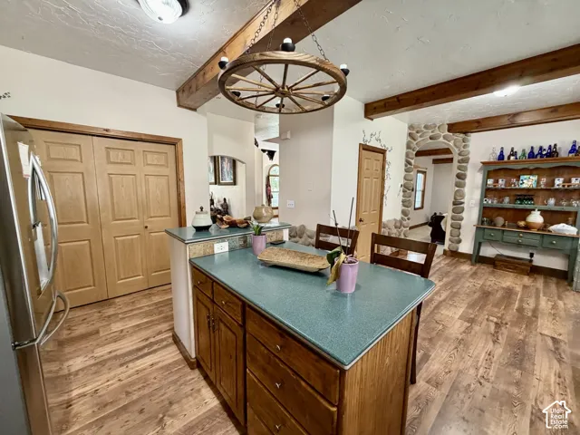 Kitchen featuring wood-finish flooring, exposed wood ceiling beams, and an island with a blue countertop
