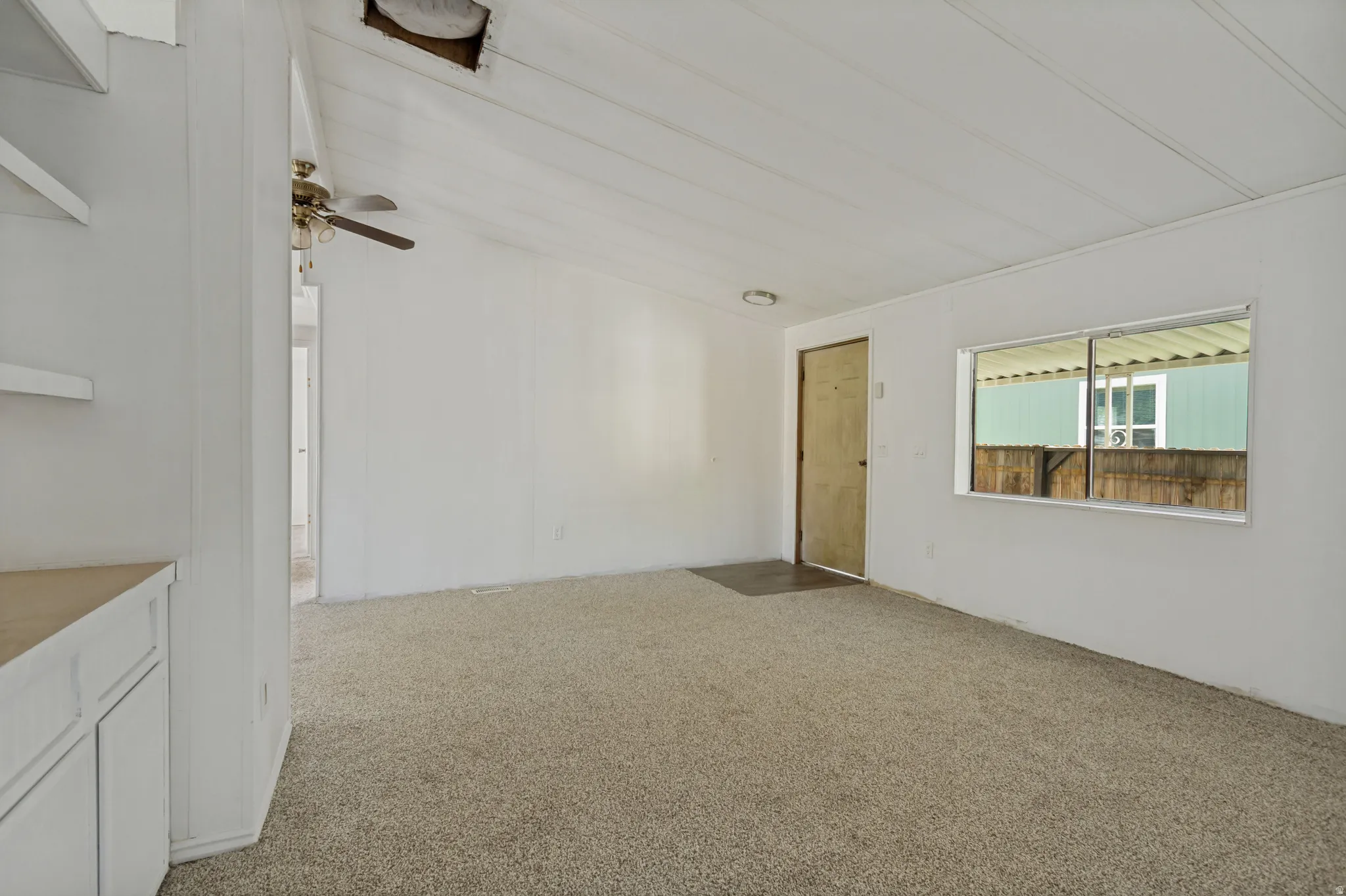 Carpeted flooring, built-in shelving, ceiling fan, and window
