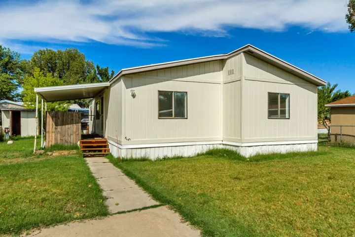 Exterior features light-colored siding, a covered entry porch, a concrete walkway, and a small outbuilding