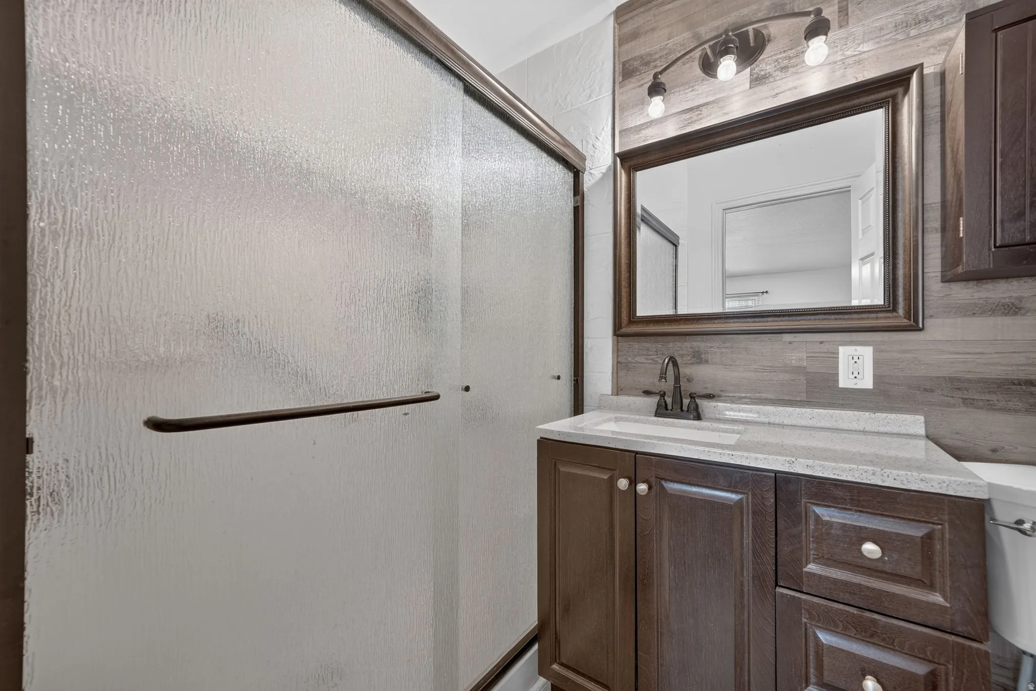 Spa-inspired bathroom featuring a wood-finish vanity with dual storage drawers, white quartz countertop, and brushed nickel faucet