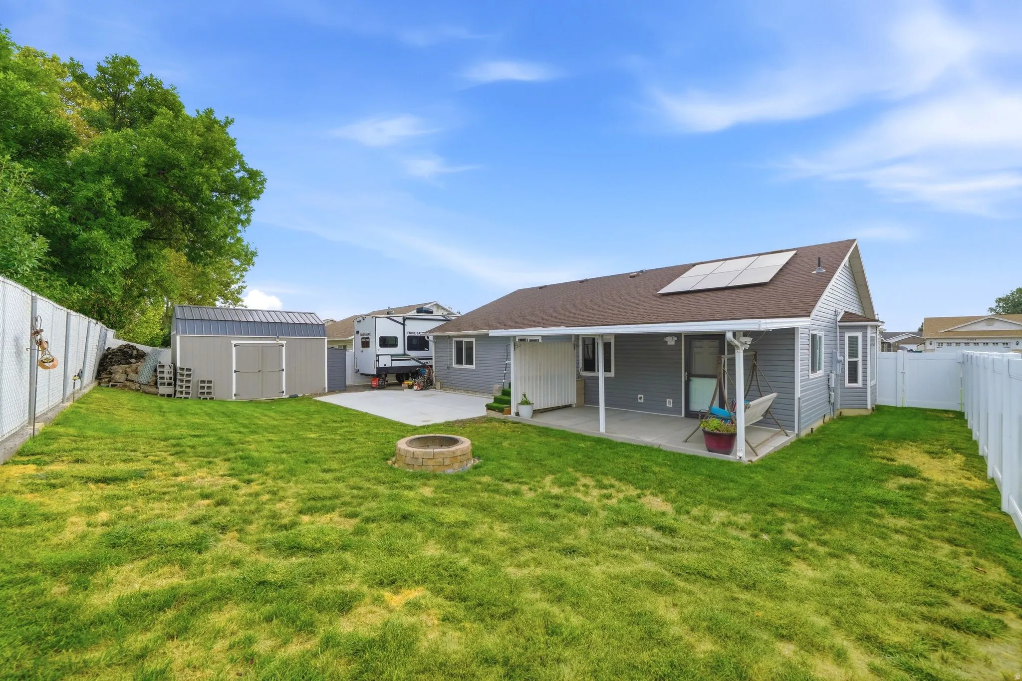 Expansive yard featuring a large patio, built-in fire pit, and a detached shed