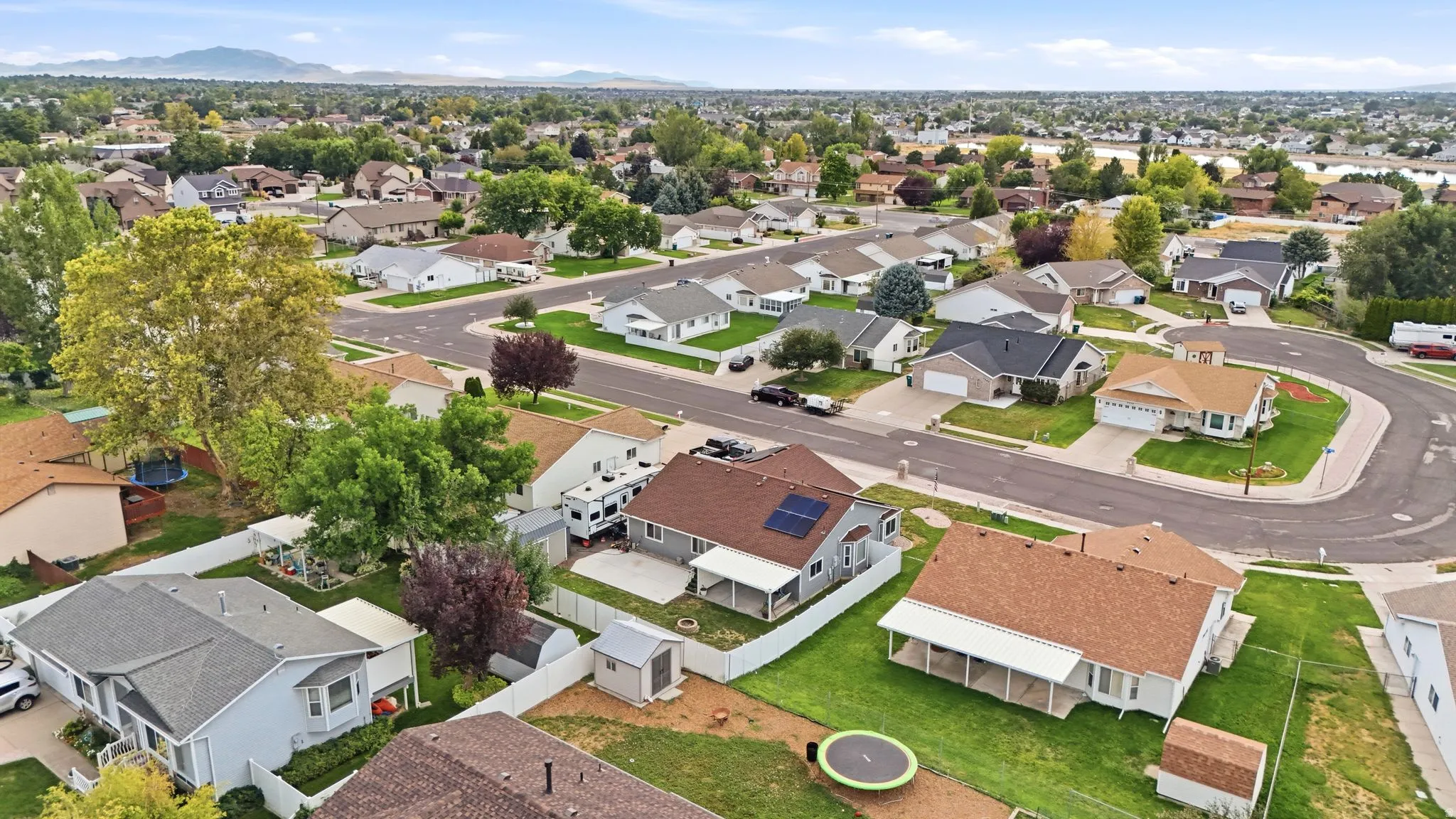 Aerial view showcasing a well-appointed residence with a brick exterior, situated on a generous lot featuring mature landscaping and established trees