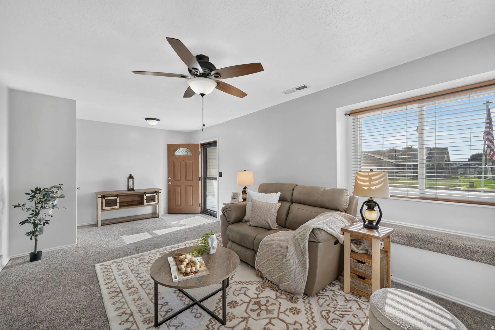 Carpeted living area featuring a ceiling fan, a window with blinds, and a built-in window bench