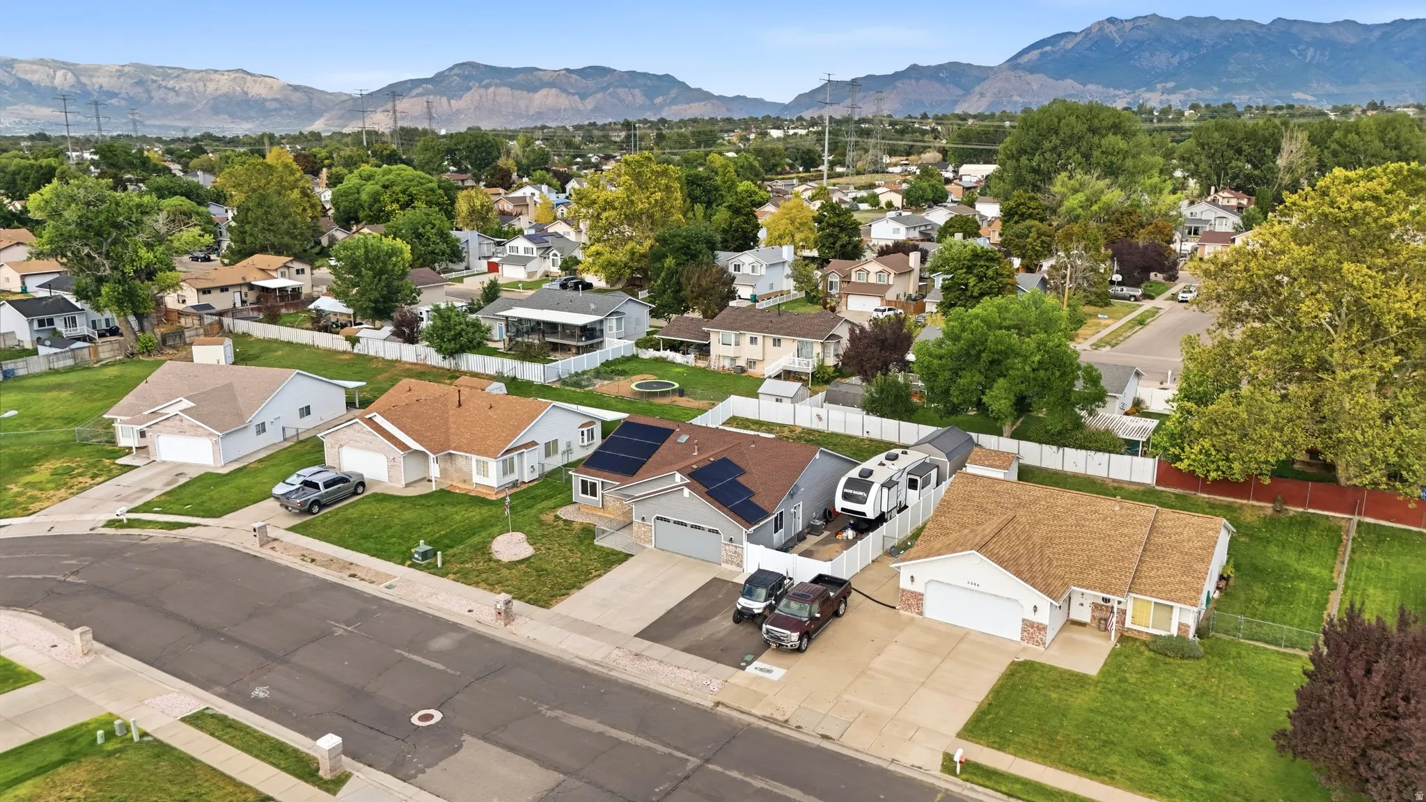Paved street frontage with curb, concrete driveway, and front yard landscaping