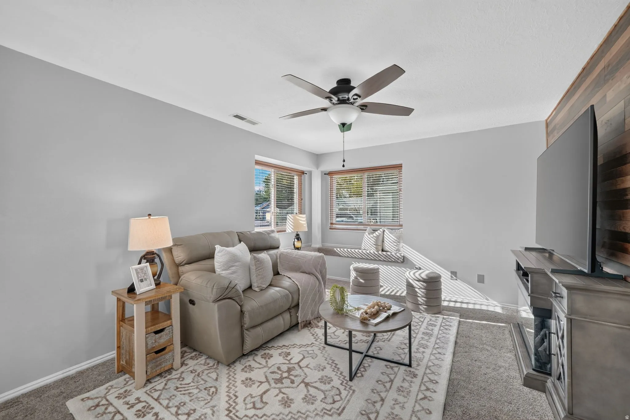 Bright and airy family room featuring expansive windows with natural light, neutral wall finishes, and plush seating areas