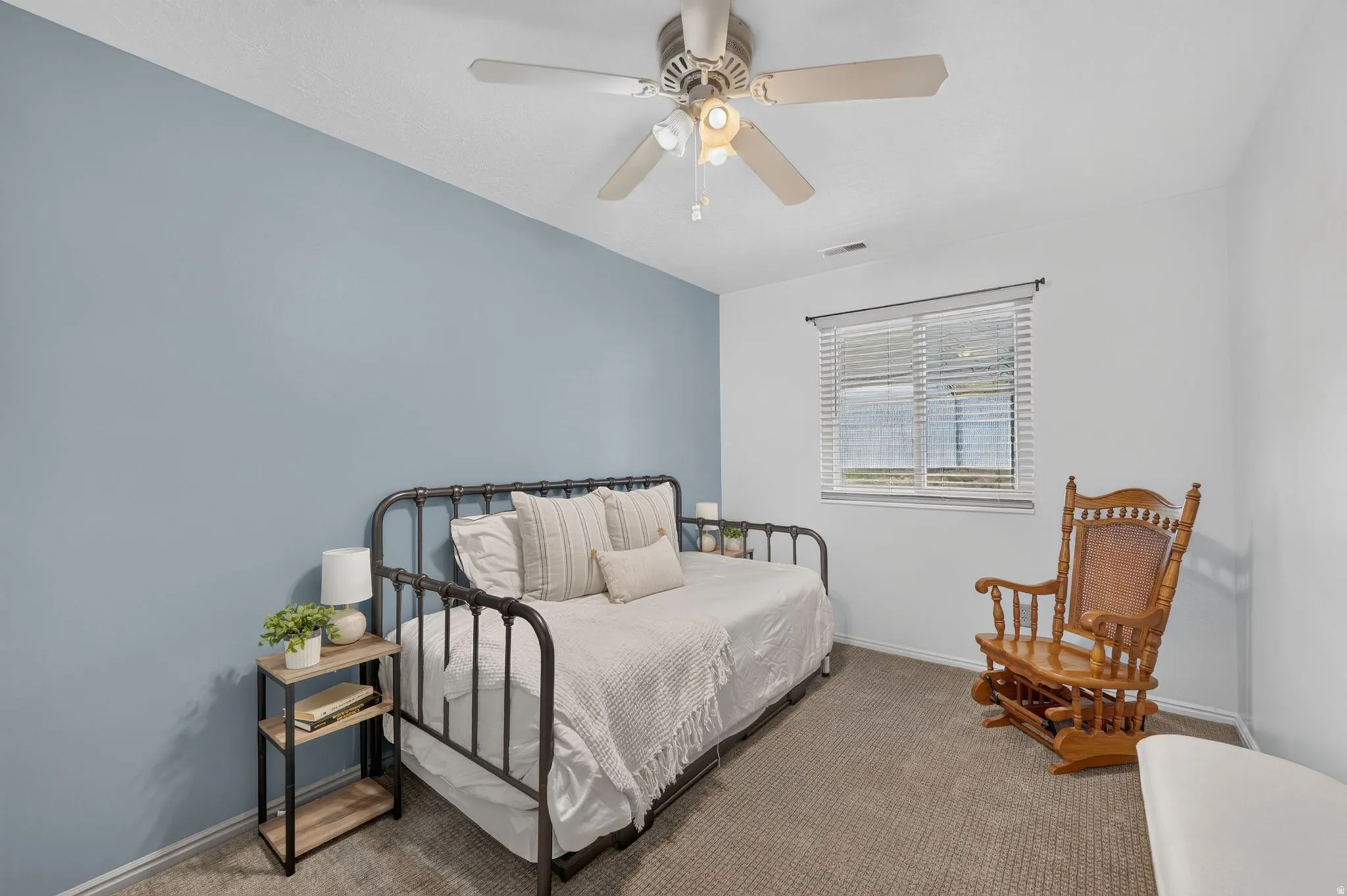 Ceiling fan with integrated lighting, window with blinds, and neutral carpet flooring