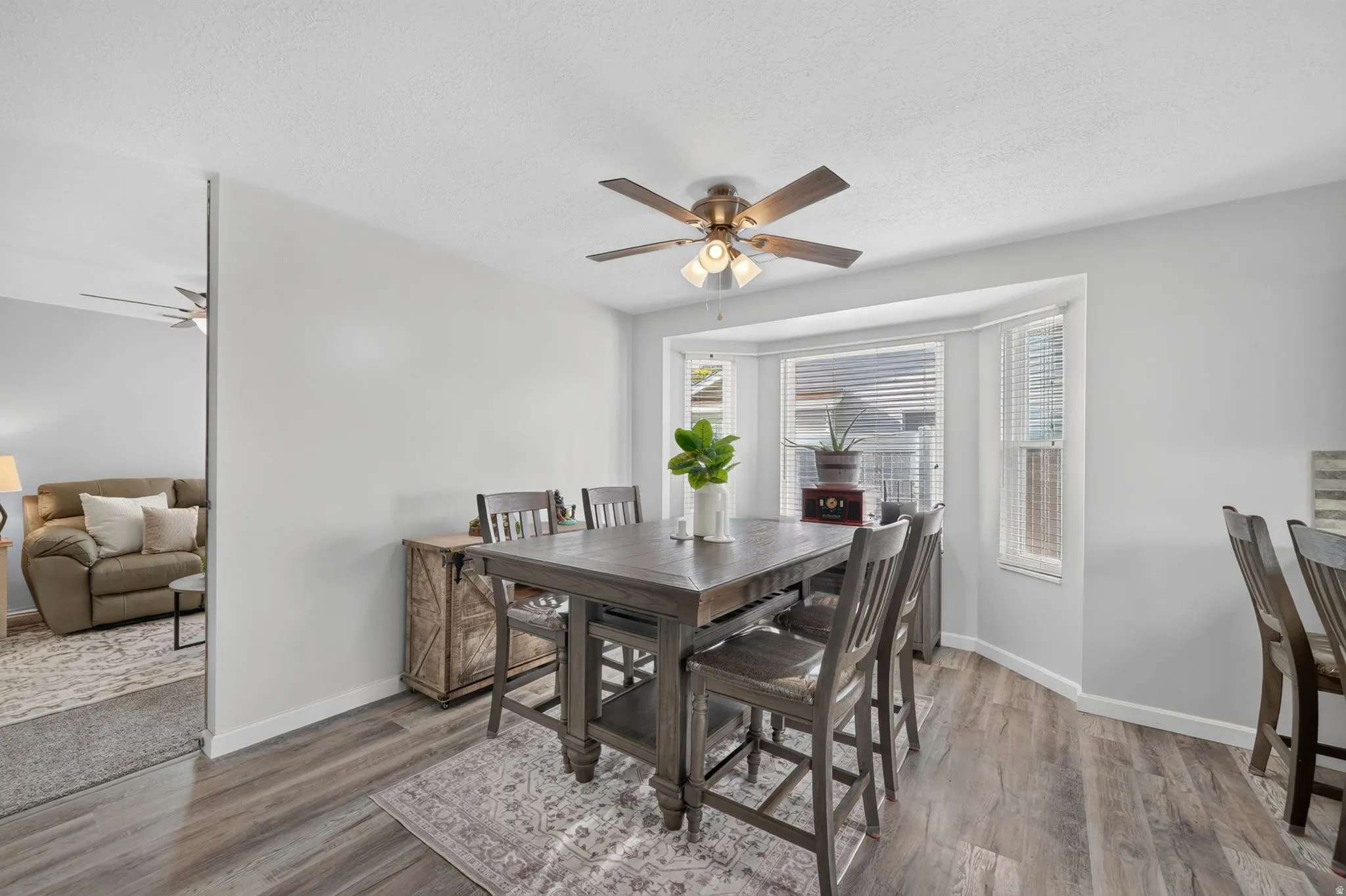 Dining area showcasing wood-finish flooring, a dark wood table with seating for six, and a ceiling fan with integrated lighting