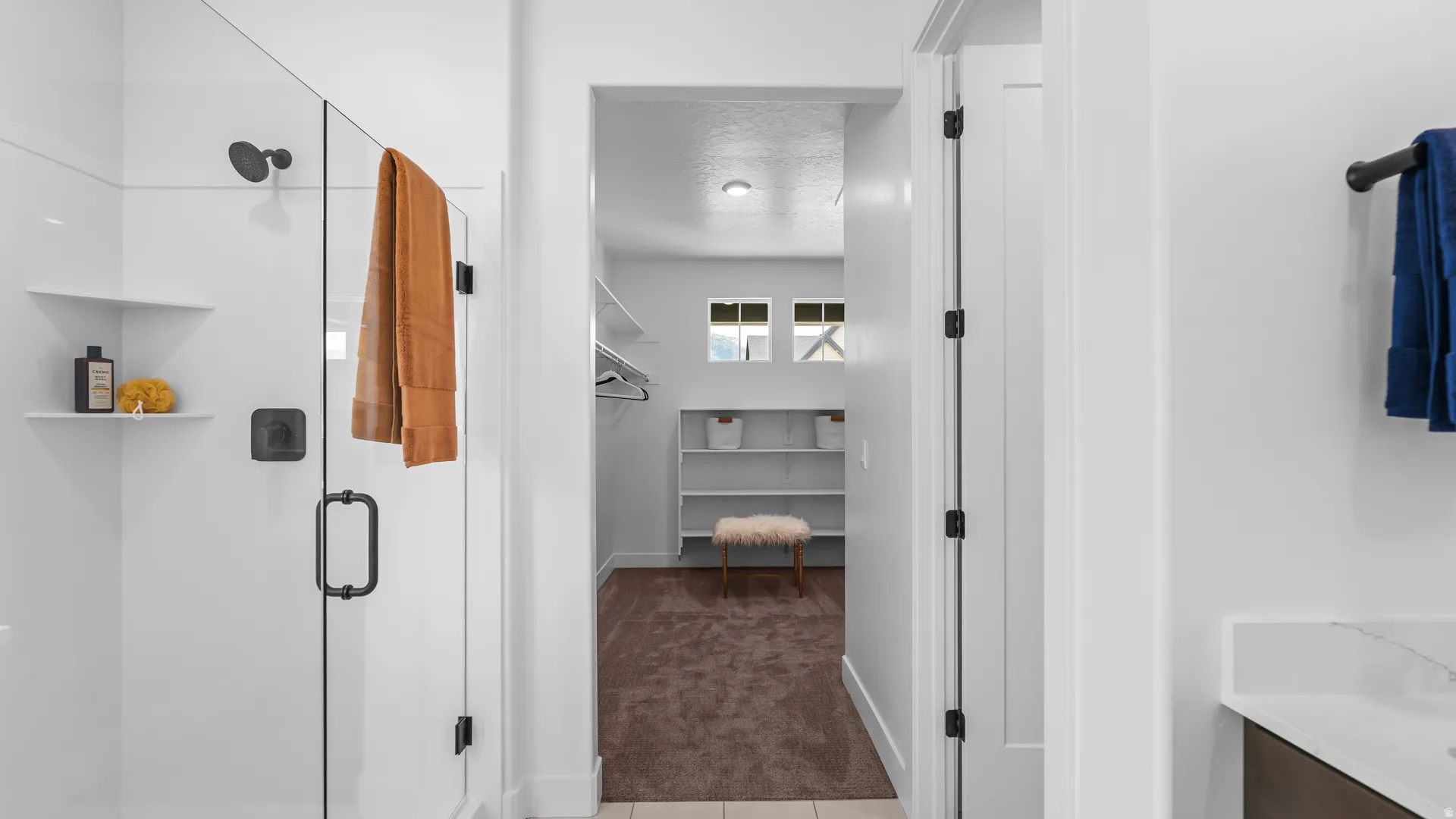 Glass-enclosed shower with matte black fixtures and built-in shelving