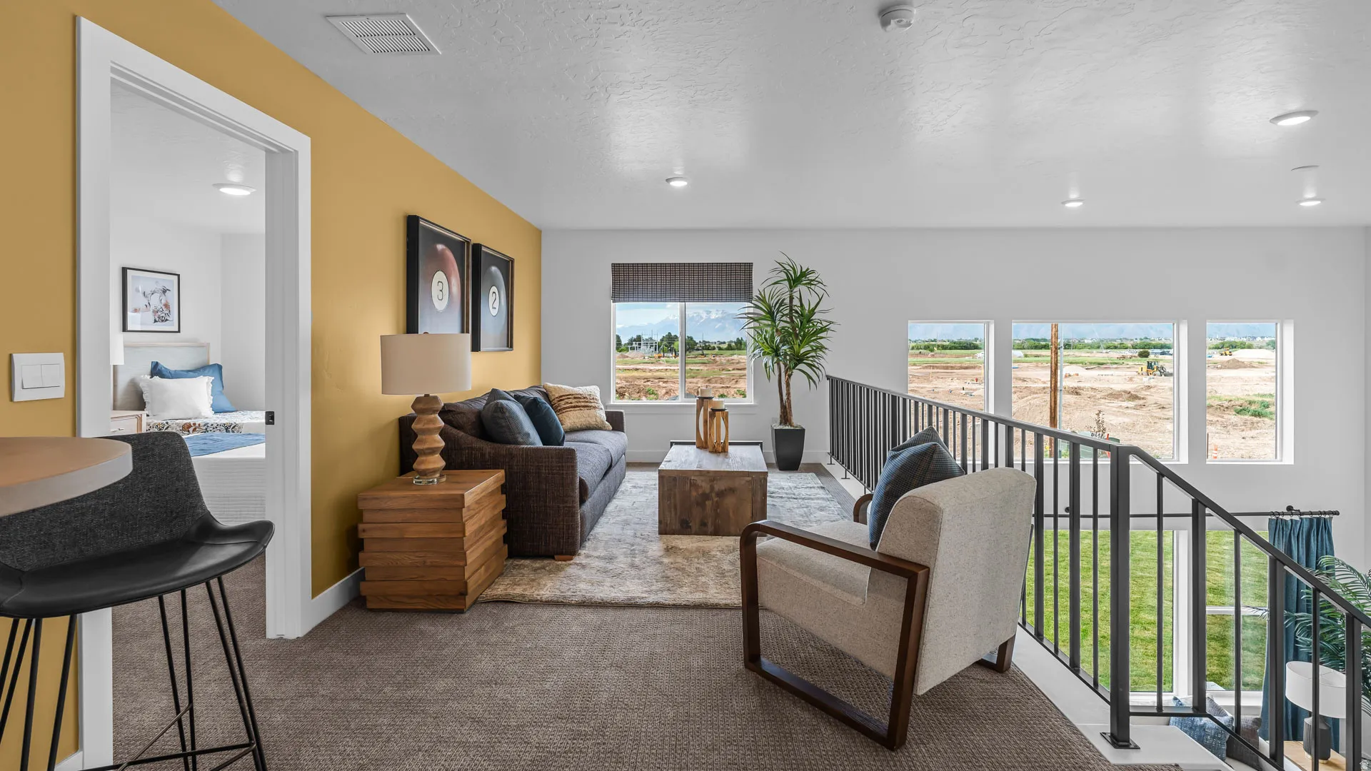 Carpeted loft area with recessed lighting, multiple windows, and dark metal railings