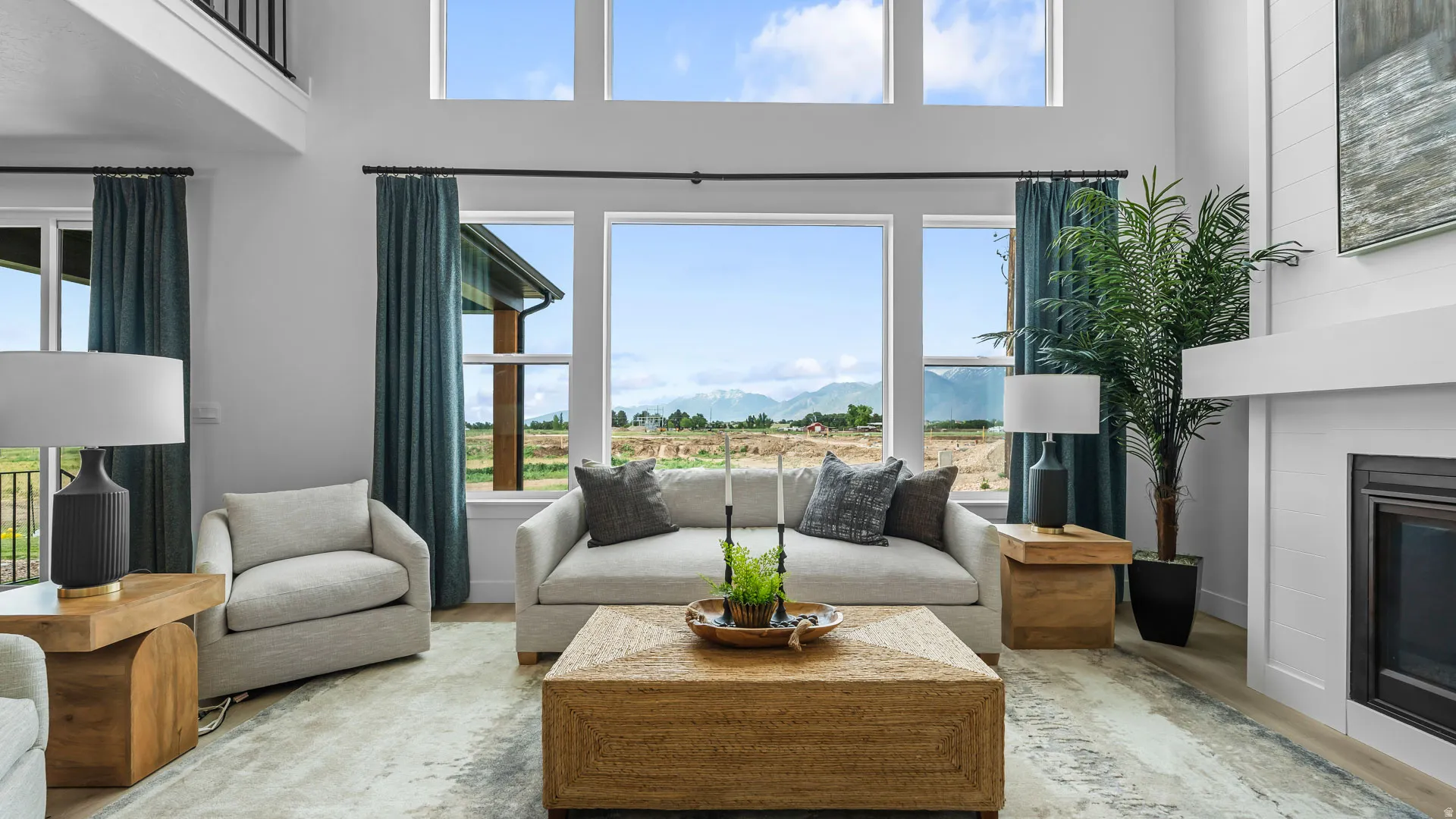 Two-story living area with high ceilings, featuring a built-in fireplace, large windows, and light wood-finish flooring