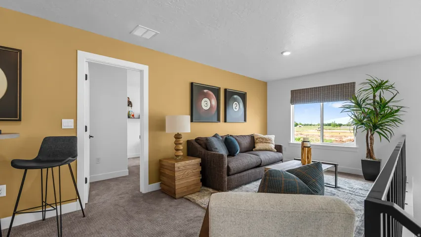 Carpeted flooring, white trim, open doorway, window with blinds, and black metal railing