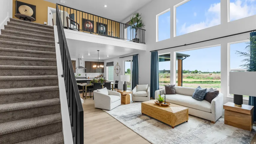 Two-story living area with expansive windows, a second-story balcony, and wood-finish flooring