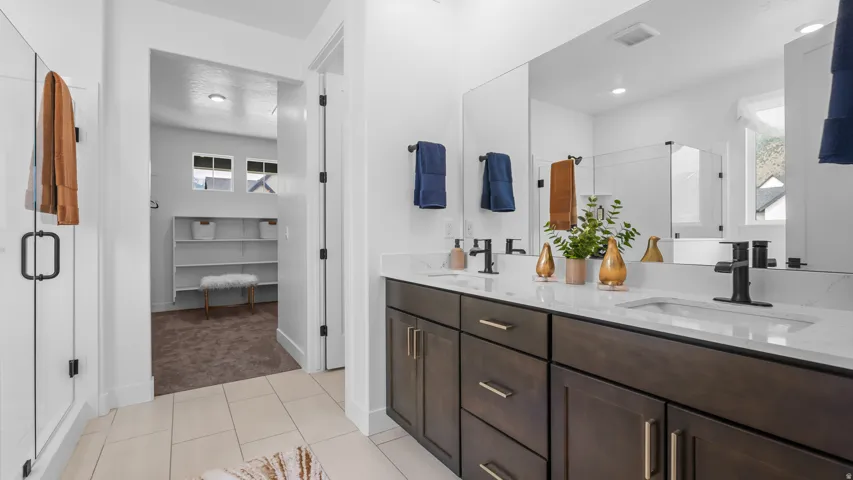 Dual vanity with dark wood-finish cabinetry, white countertop, and matte black fixtures