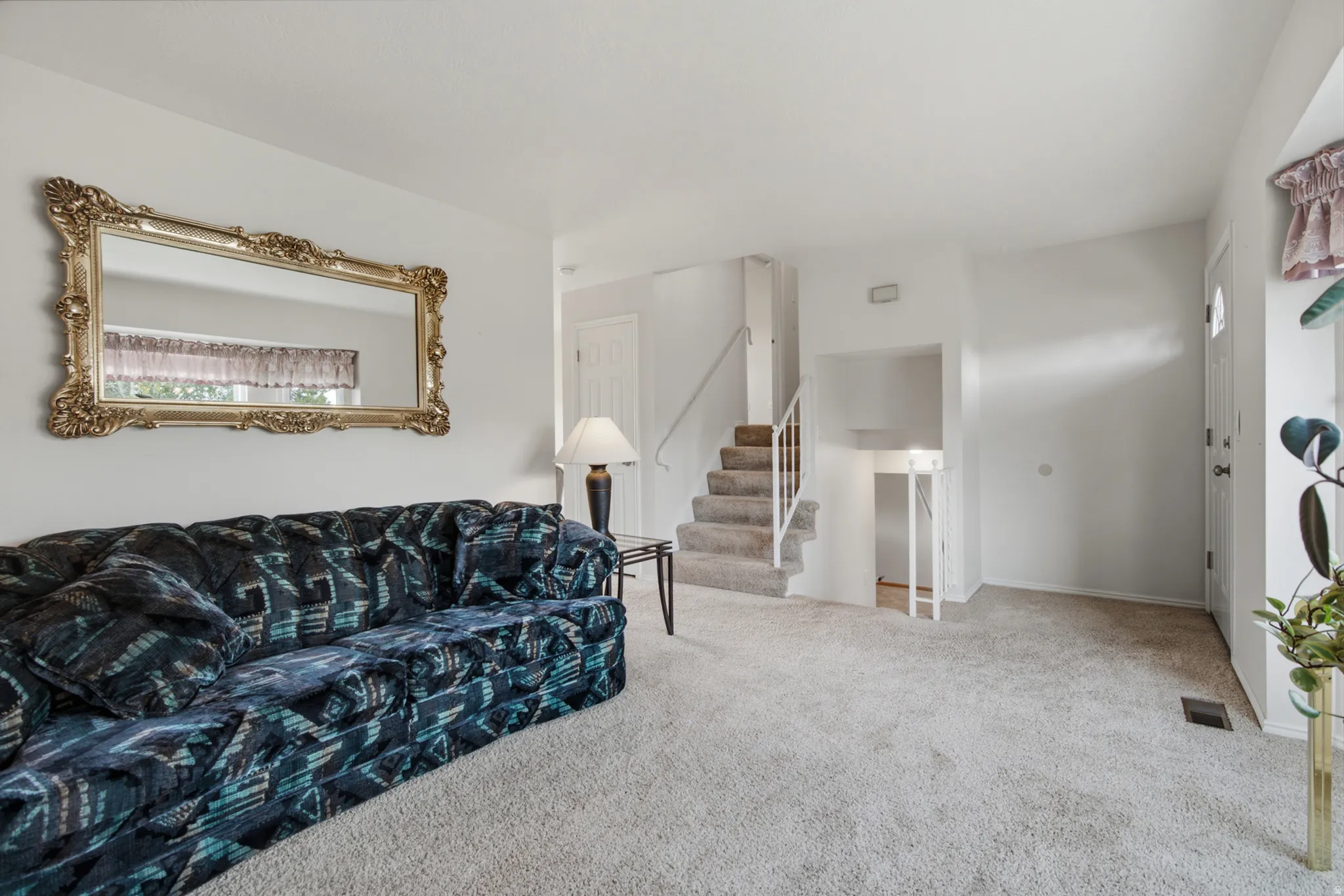 Carpeted flooring throughout, white painted walls, and a staircase with a white railing