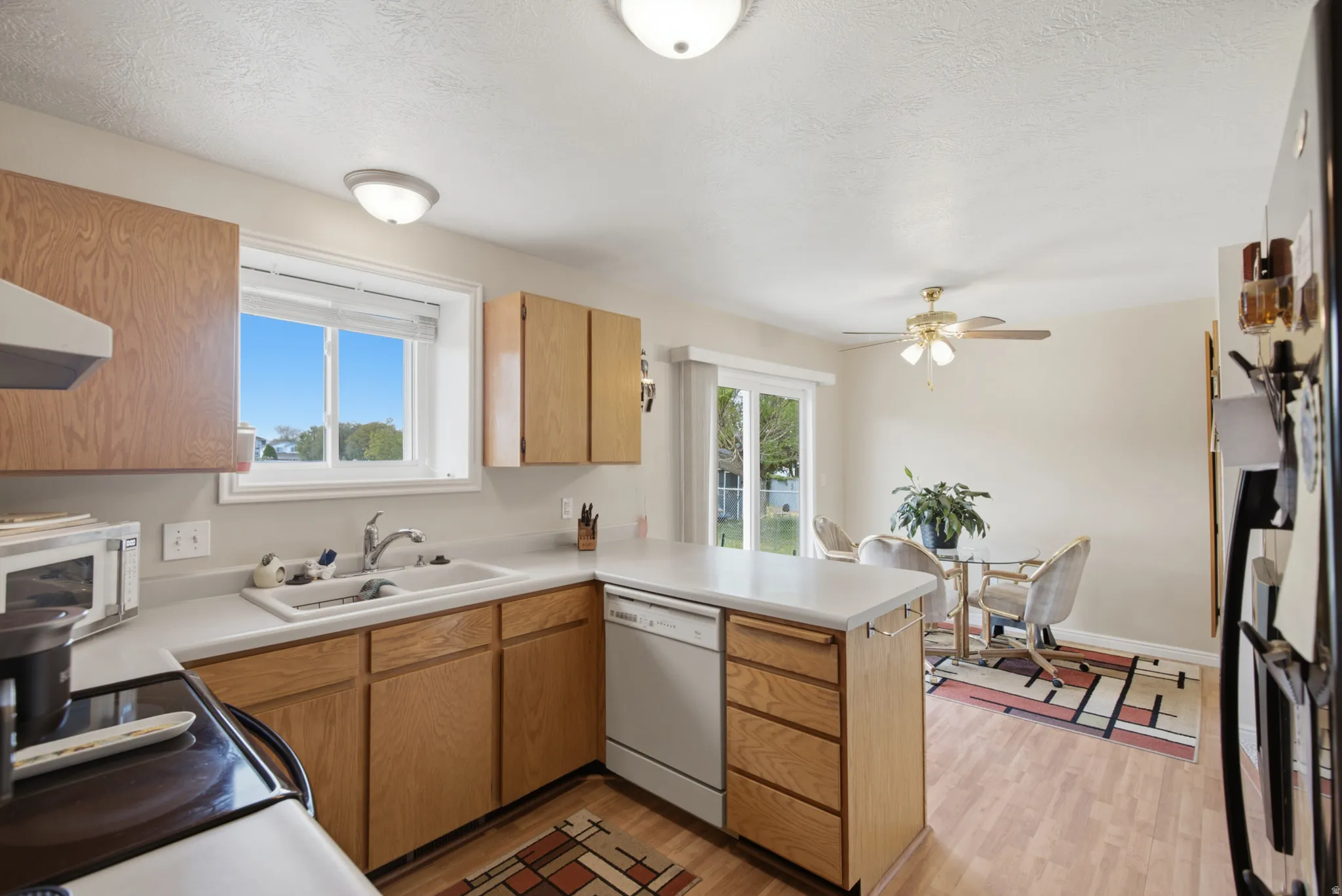 Bright, open kitchen featuring warm wood cabinetry, white countertops, stainless steel appliances, and a central island with additional storage