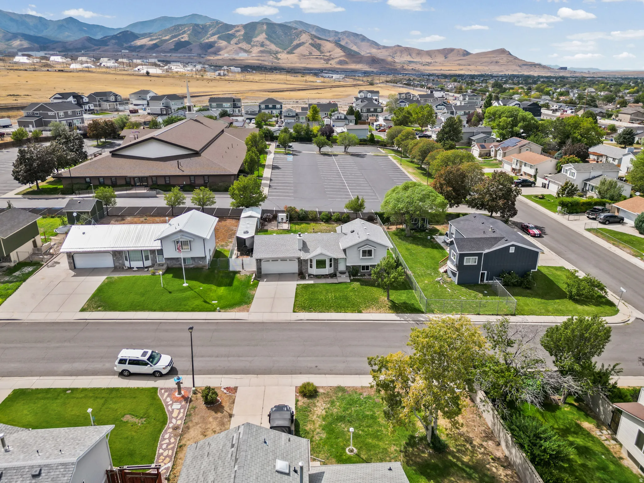 Mountain backdrop, established neighborhood, residential street, paved driveway, green lawn