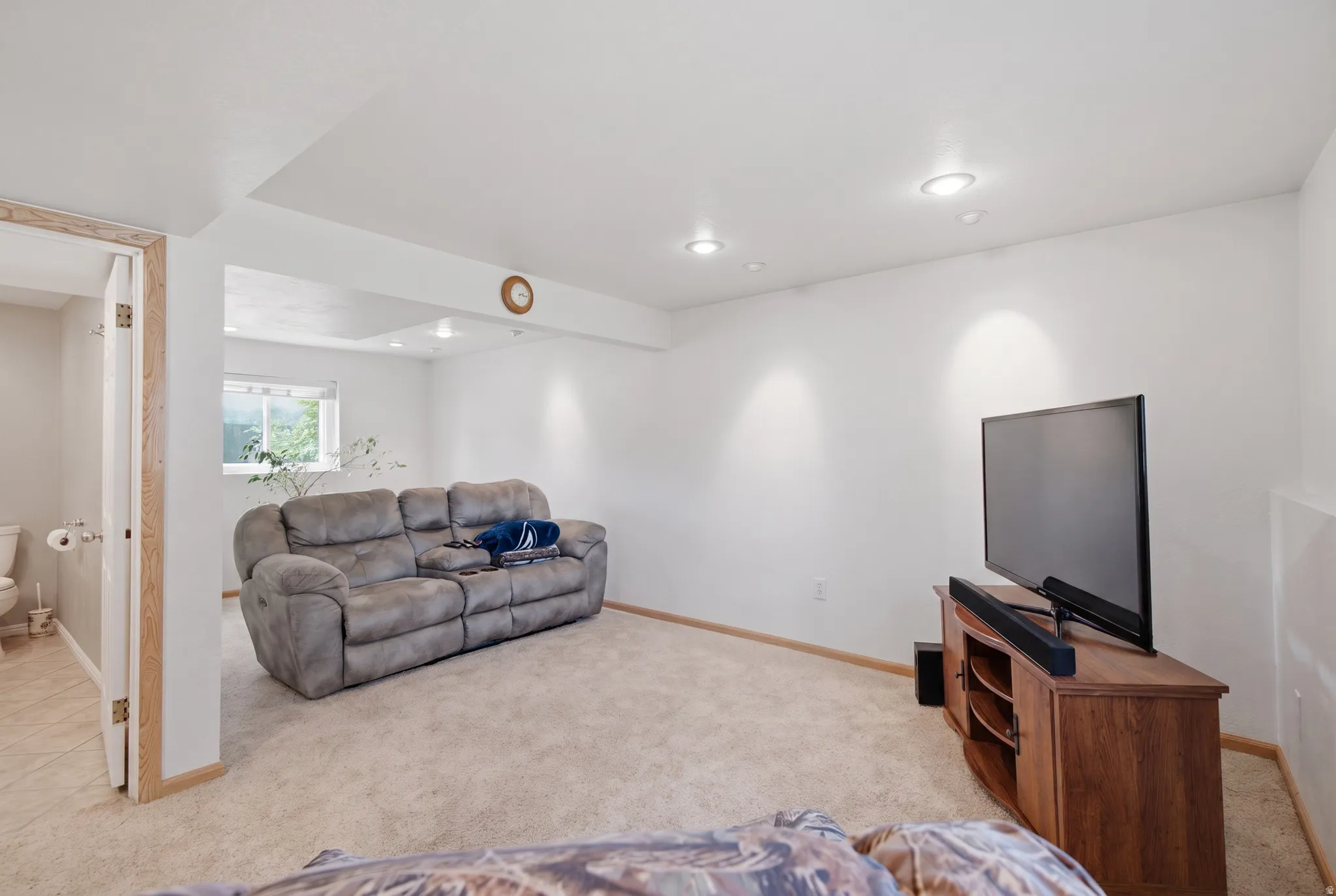 Recessed ceiling lighting, light-colored carpeting, a window, and wood-finish trim