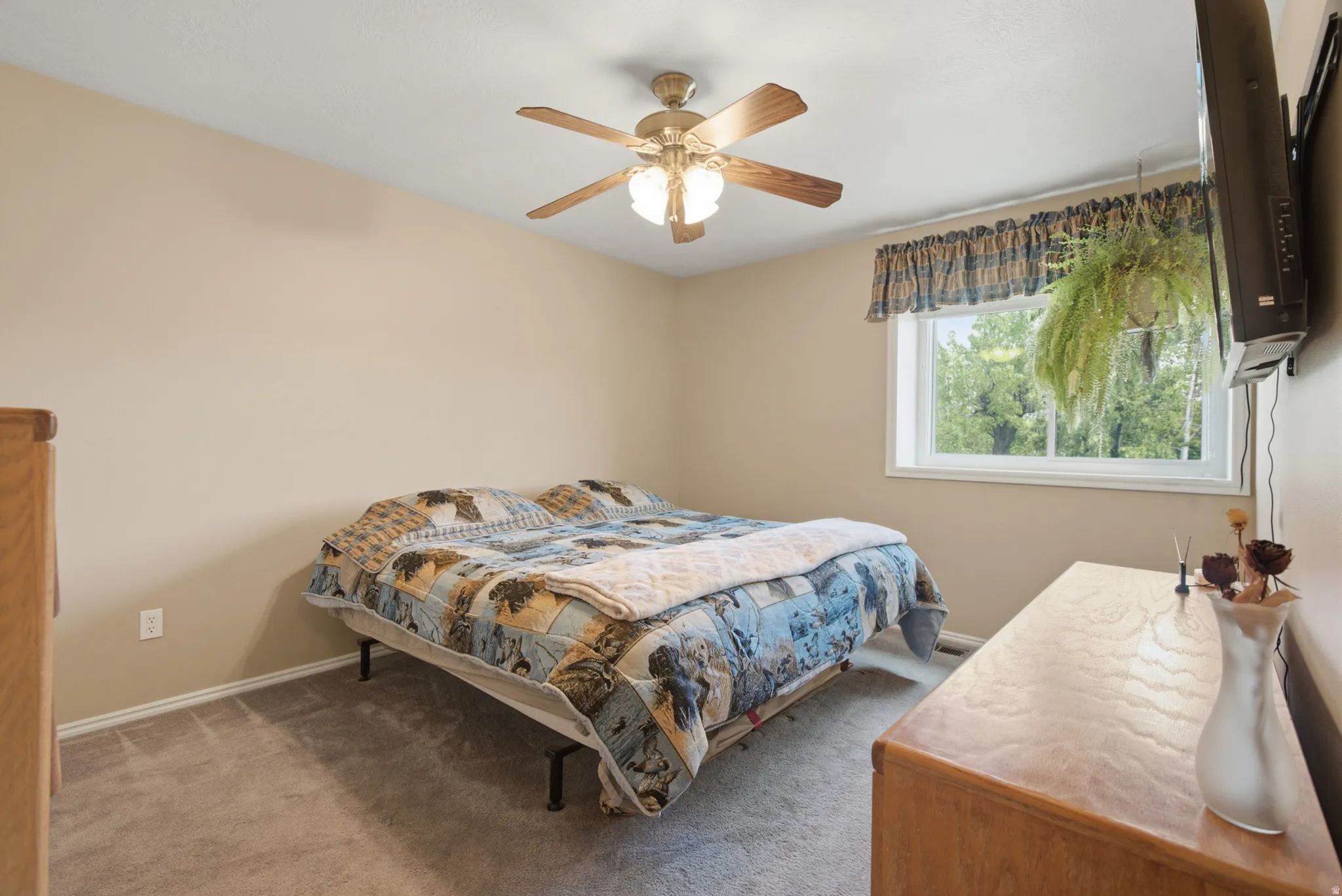 Neutral tone wall color, ceiling fan with integrated lighting, carpeted flooring, and a window