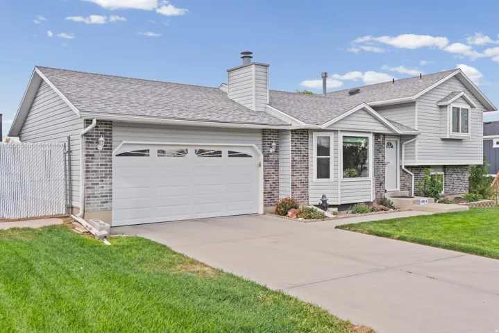 Exterior featuring light grey siding, dark grey brick accents, an attached two-car garage, and a concrete driveway